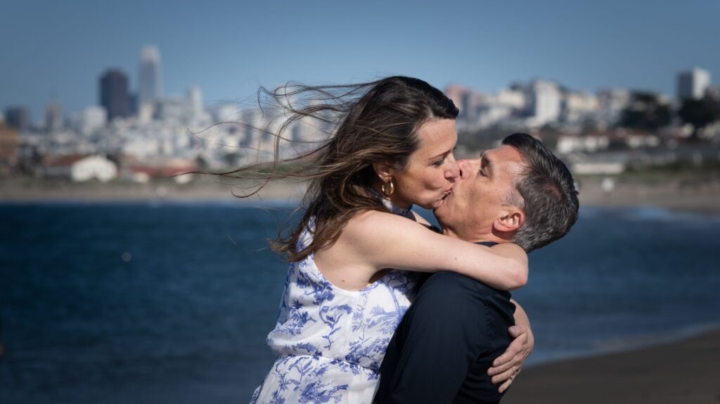 Couple embraces during an engagement photo session near the Golden Gate Bridge at Crissy Field.
