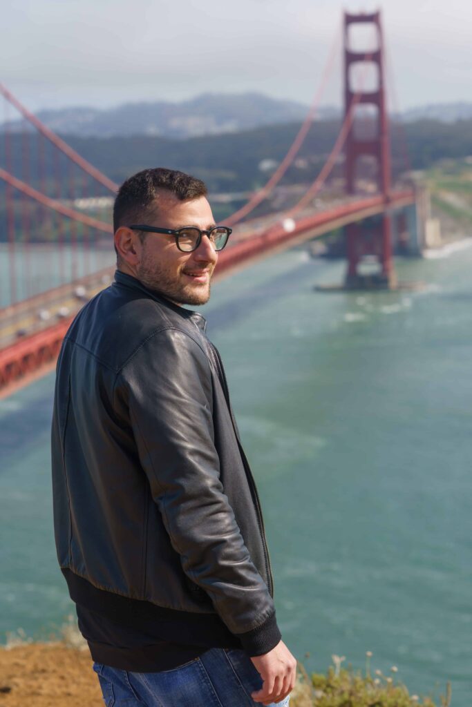 Man posing confidently in front of the Golden Gate Bridge during a San Francisco headshot session