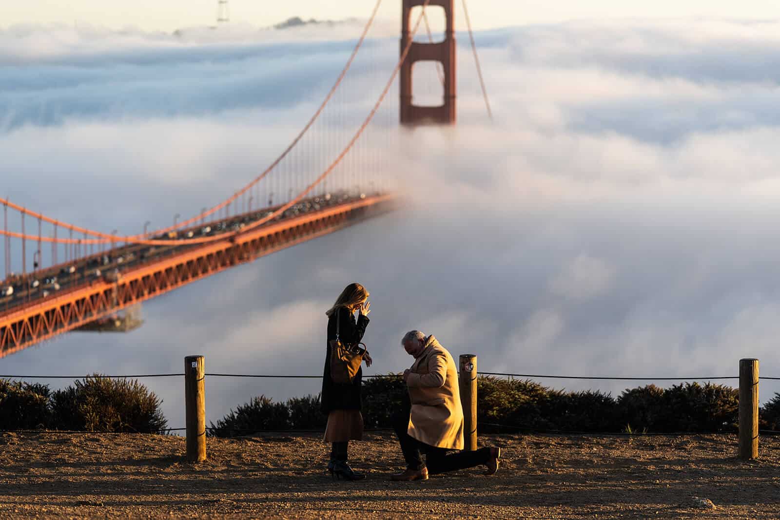 Man proposes to woman at Battery Spencer with Golden Gate Bridge in the background, fog rolling in.