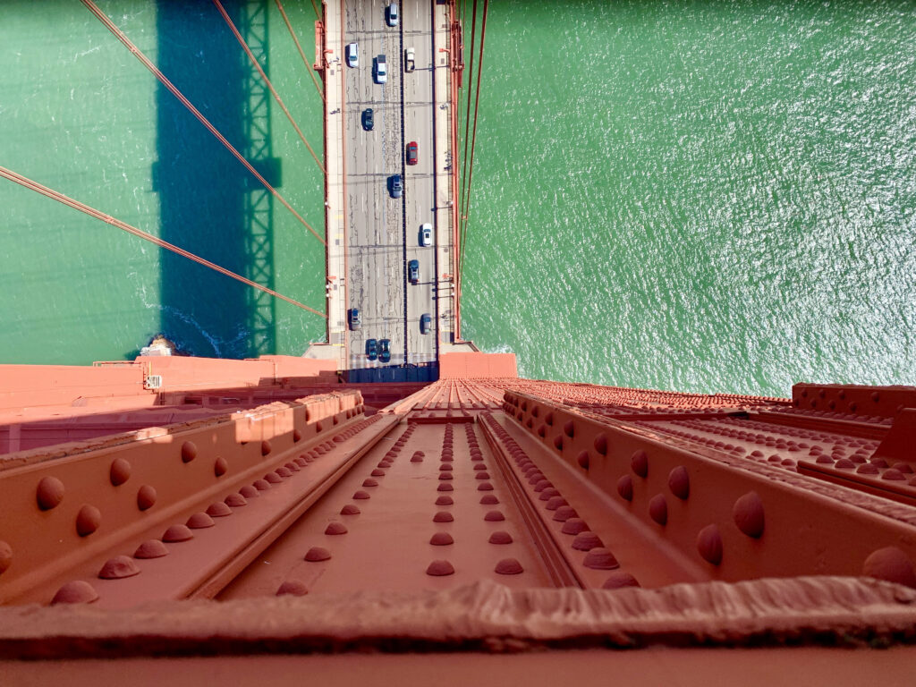 Top-down view from Golden Gate Bridge showing red structure and turquoise bay water in San Francisco