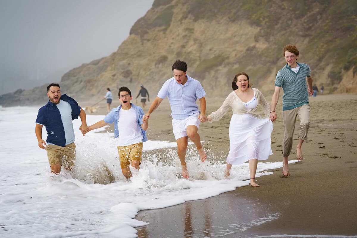 Family running through the surf at the beach during a fun and candid photo session