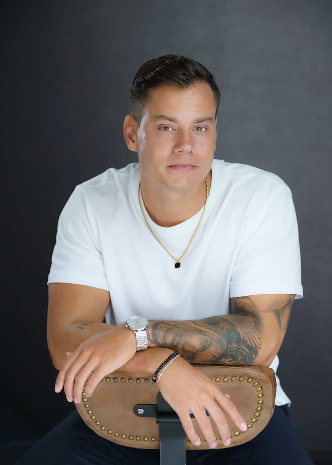 Tattooed man in a white shirt seated for a relaxed, modern professional headshot