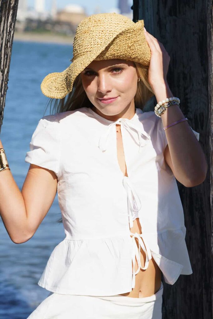 Woman in a straw hat and white outfit smiling outdoors by the water — natural light portrait in San Francisco