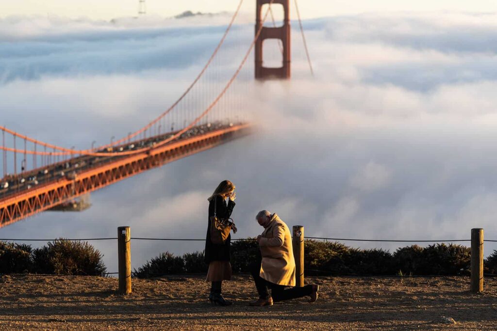 Man proposes to woman at Battery Spencer with Golden Gate Bridge in the background, fog rolling in.