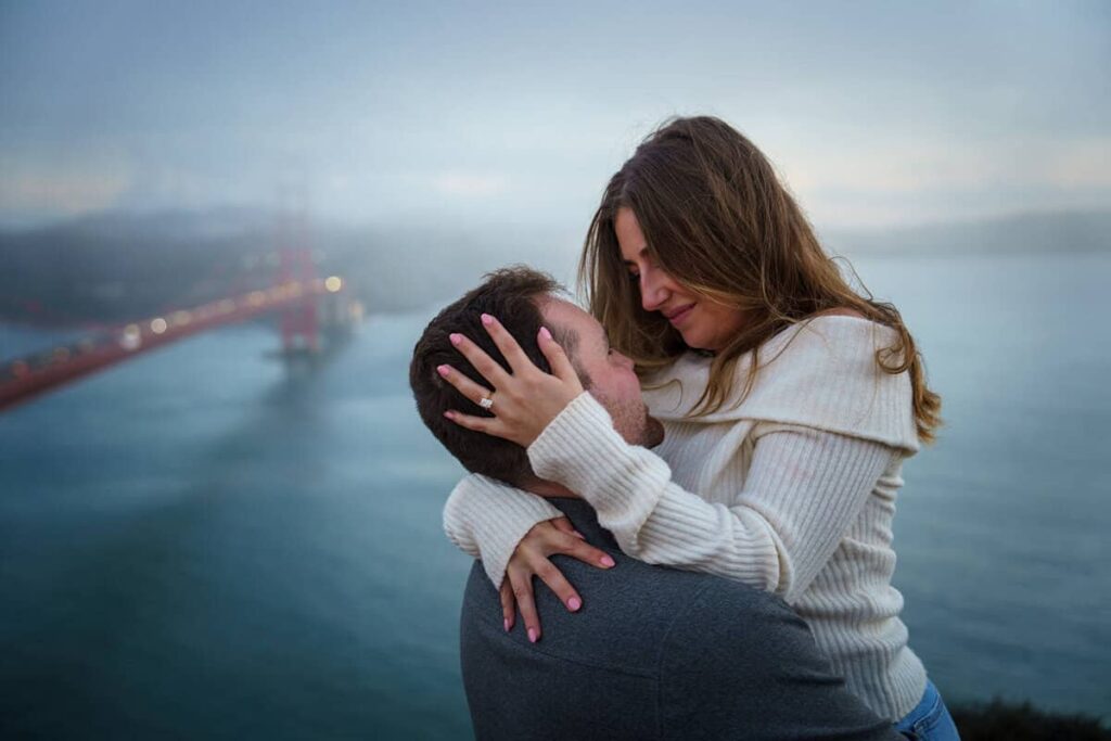 Couple embracing with the Golden Gate Bridge in the background on a foggy San Francisco morning