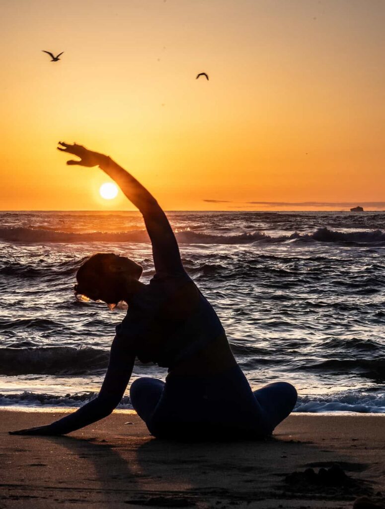 Silhouette of a young girl jumping on the beach at sunset in San Francisco.