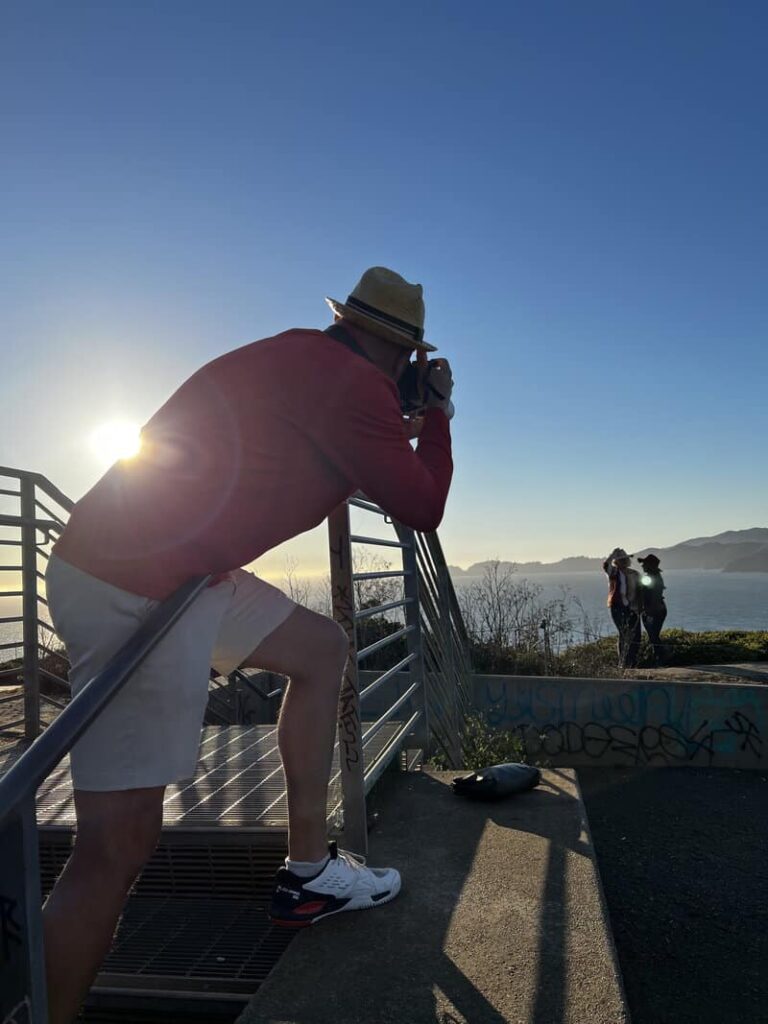 Photographer capturing a portrait session at Baker Beach during golden hour in San Francisco