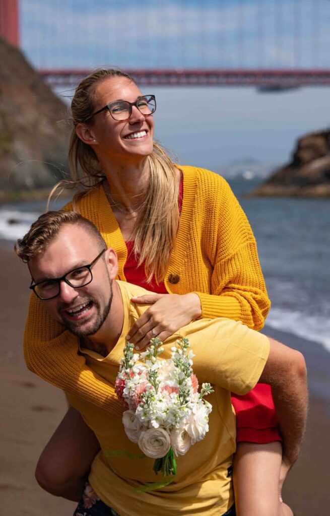 Engaged couple laughing at Kirby Cove with the Golden Gate Bridge in the background.